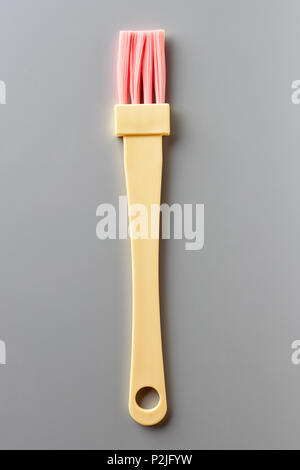 Yellow and pink pastry brush on grey background, from above Stock Photo