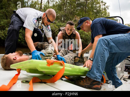 Local emergency technicians move a simulated victim onto a back-board for transportation during a mass casualty exercise Sept. 28 at Eglin Air Force Base, Fla.  Three groups of Soldiers in zodiac boats encountered a simulated civilian and Army boat crash.  The Soldiers acted as first responders to triage the victims, coordinate to receive help and get the wounded to local emergency technicians.  (U.S. Air Force photo/Samuel King Jr.) Stock Photo