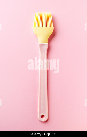 Pink and yellow silicone pastry brush on pink background, top view Stock Photo