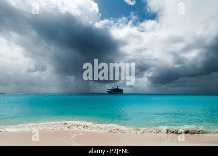 The cruise ship drifting near uninhabited island Half Moon Cay under the cloudy sky (Bahamas). Stock Photo