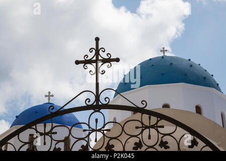 wrought-iron gate with cross in front of blue painted domed church chapel on greek isalnd santorin Stock Photo