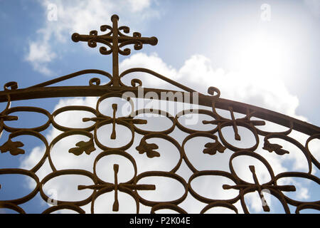 cloudy summer sky seen upwards through wrought-iron gate with christian cross symbol on Santorin Stock Photo