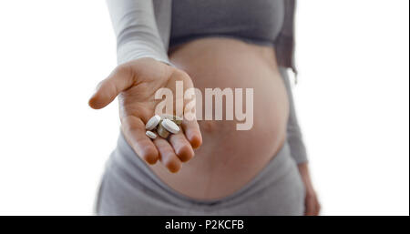 Pregnant woman belly holding pills in hand Stock Photo