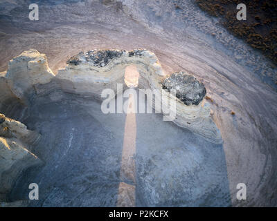 Elevated view of the natural arch formation at Monument Rocks chalk pyramids with a beam of sunlight shining through it on the ground in Kansas Stock Photo