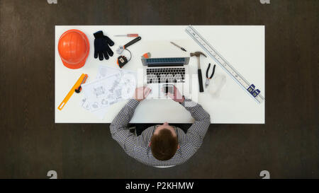 Office engineer using mobile phone sitting at his desk Stock Photo