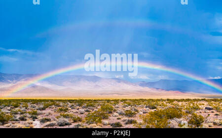 Beautiful rainbow over an American desert with hills and mountains in the background and a clear blue sky for copyspace Stock Photo