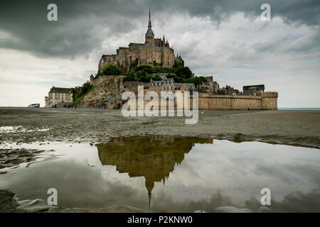 View of the Mont Saint Michel. Reflection in water at the foreground, dramatic sky. Stock Photo
