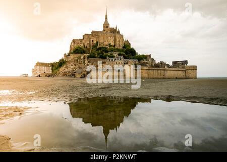 View of the Mont Saint Michel. Reflection in water at the foreground, Sunlight effect on the left. Stock Photo