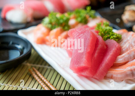 Mixed sliced fish sashimi in white plate. Sashimi Salmon and Tuna set with Tuna, flying fish roe caviar and Foie Gras closeup. Japan restaurant menu Stock Photo