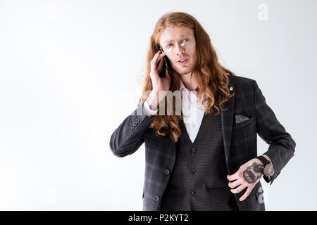 stylish tattooed businessman with curly hair talking by smartphone isolated on white Stock Photo