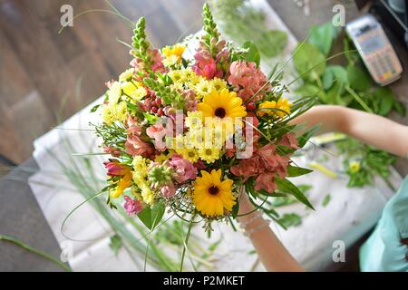 woman binds flower bouquet in florist Stock Photo