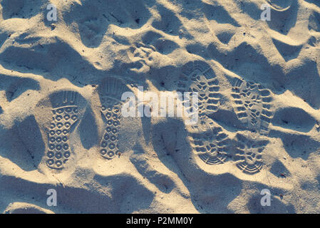 Two pairs of steps in a sand. Love trails. Togetherness. Selective focus Stock Photo