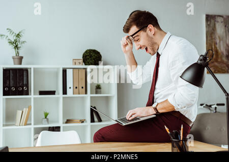 excited businessman using laptop in modern office Stock Photo