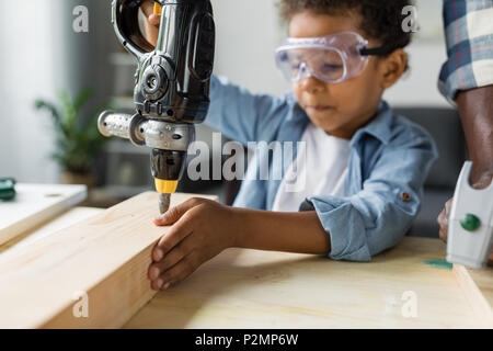 cute african boy in protective eyeglasses playing with toy drill Stock Photo