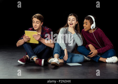 teenagers interested looking at friend using tablet on black Stock Photo