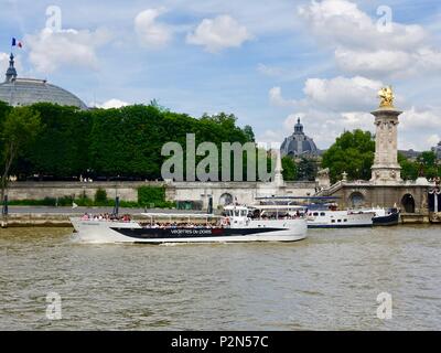 Rooflines of the Grand Palais and Petit Palais, seen across the Seine River as a tourist boat passes by the Pont Alexandre III, bridge, Paris, France. Stock Photo