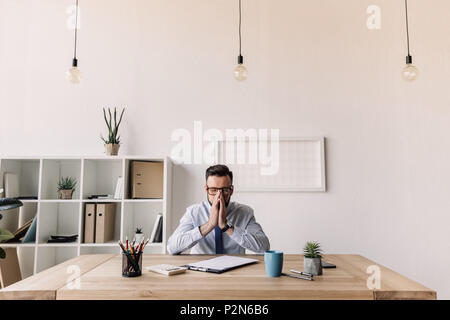 thoughtful bearded businessman sitting at table in modern office Stock Photo