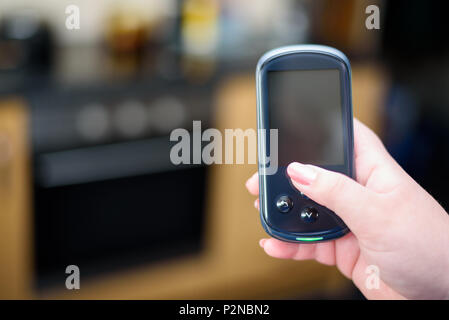 Woman holding a Domestic Energy Smart Meter unit in a kitchen Stock Photo