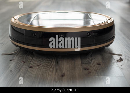 robotic vacuum cleaner on laminate wood floor Stock Photo