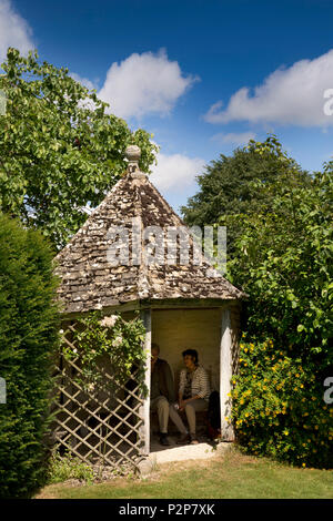 UK, England, Oxfordshire, Kelmscott Manor, William Morris’ home, visitors in shady front garden gazebo with stone tiled roof Stock Photo