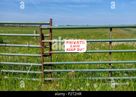 Sign on gate leading to a field reading Private Land Keep Out Stock Photo