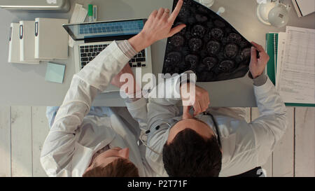 Two doctors men examine magnetic resonance imaging. Top view Stock Photo