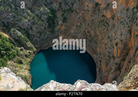 Red Lake Imotski Croatia, Beautiful nature and landscape photo of very big,  deep sinkhole in Dalmatian mountains. Nice sunny summer day. Stock Photo