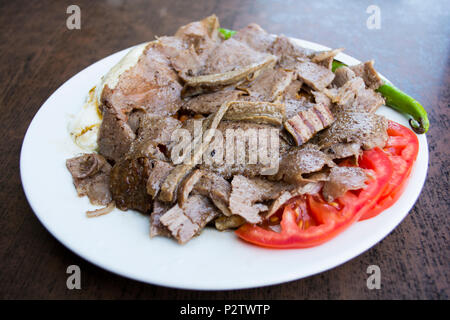 turkish iskender kebab with garnish on a wooden surface at restaurant Stock Photo