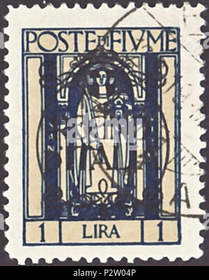. Stamp of Fiume; 1924; definitive stamp after the annexation of Fiume (Rijeka) to the Kingdom of Italy in February 1924; stamp of Fiume from 1923 with overprint; framed rectangle drawing of Saint Veit (also: 'St.Vid') - the patron saint of the town Rijeka; overprint of the type 'REGNO / D' ITALIA' (= 'Kingdom of Italy') in decorated circle with coat of arms of the Kingdom of Italy; postmarked Stamp: Michel: No. 190 (= No. 162 from 1923 with overprint) Color: two-color print; dark blue on dull beige underpress; black overprint Watermark: none Nominal value: 1 Lira Postage validity: from 22 Feb Stock Photo