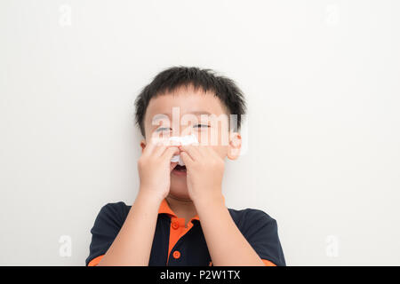 Cute little boy sneezing in tissue on white background Stock Photo