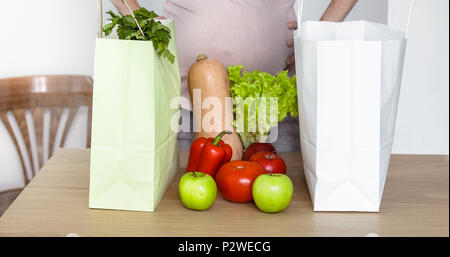 Expecting woman take out vegetables from shopping bag Stock Photo