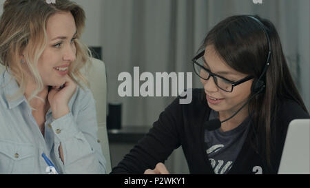 Two female colleagues happily discussing new project in the office Stock Photo