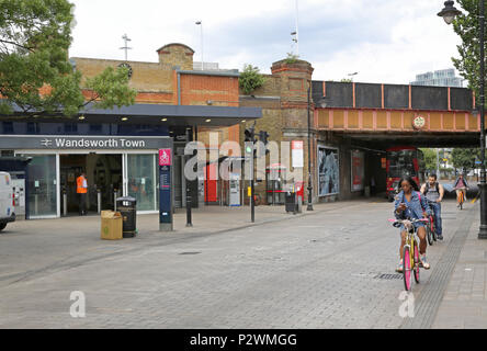 Local shopping street outside Wandsworth Town rail station, a fashionable area of southwest London, UK. Shows cyclist using mobile phone whilst riding Stock Photo