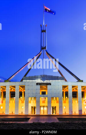 National Australian flag on flagpole on top of public government building - parliament house in Canberra on capitol hill at sunset with bright illumin Stock Photo