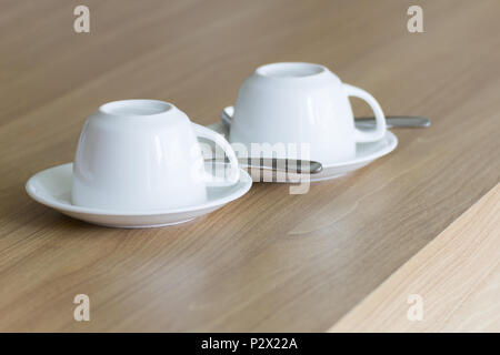 New white cups coffee set upside-down on wooden table. Stock Photo