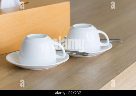 New white cups coffee set upside-down on wooden table. Stock Photo
