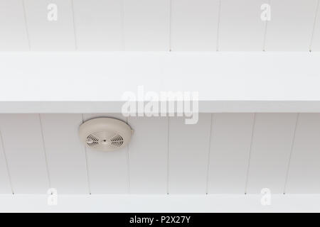 Smoke detector of fire alarm on white wooden ceiling. Stock Photo