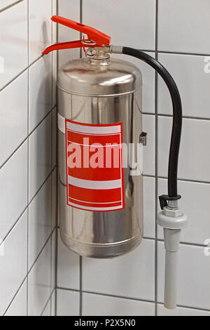 Silver fire extinguisher in building corner Stock Photo