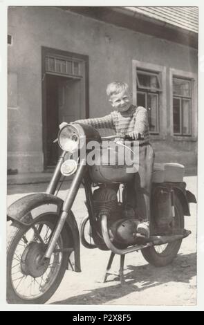 THE CZECHOSLOVAK SOCIALIST REPUBLIC - CIRCA 1960s: Vintage photo shows boy sits on the vintage motorcycle.  Retro black & white  photography. Stock Photo