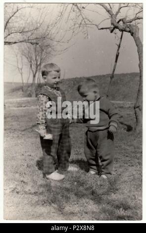 THE CZECHOSLOVAK SOCIALIST REPUBLIC - CIRCA 1960s: Vintage photo shows two  small boys play outdoors. Funny and cute photo. Retro black & white  photography Stock Photo
