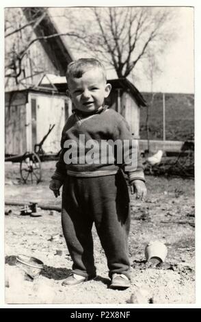 THE CZECHOSLOVAK SOCIALIST REPUBLIC - CIRCA 1970s: Vintage photo shows a small boy stands in the backyard.  Retro black & white  photography. Stock Photo