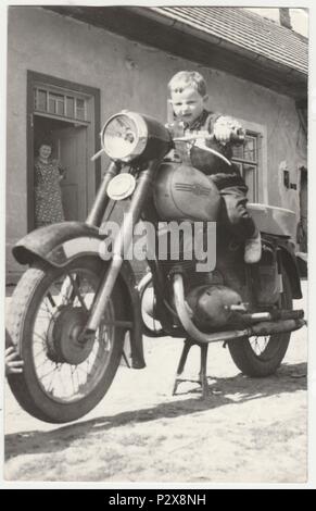 THE CZECHOSLOVAK SOCIALIST REPUBLIC - CIRCA 1960s: Vintage photo shows boy sits on the vintage motorcycle.  Retro black & white  photography Stock Photo