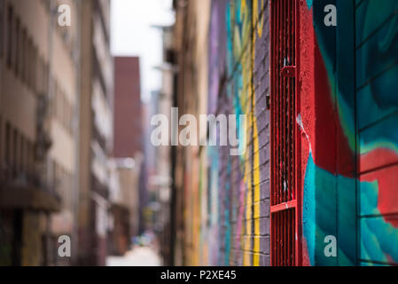 An abstract view of an inner city allyway in Johannesburg, brightly decorated with colourful graffiti, focussed on the foreground and blurred in the d Stock Photo