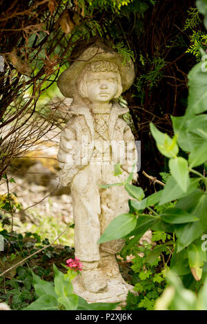 A stone figurine of a boy set near a garden pond. Lancashire North West England UK GB Stock Photo