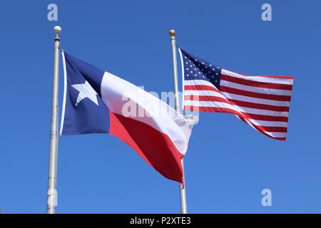 Texas flag, Lone Star State flag and United States of America US flag against blue sky background Stock Photo