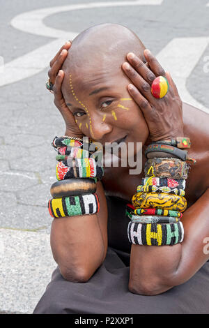 A beautiful woman wearing approximately 18 bracelets on a warm day in Union Square Park in Manhattan, New York City Stock Photo