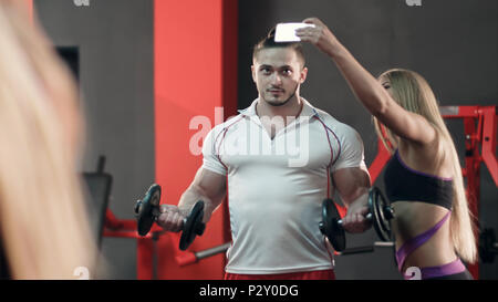 Sporty woman taking selfie with strong man working out in the gym Stock Photo