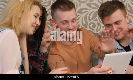 Four hipsters communicate via video conference using tablet Stock Photo