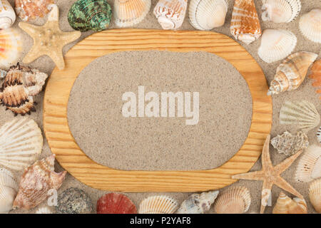 Wooden frame cut from a solid board, lies seashells and starfish on the sand. With space for your text. View from above Stock Photo