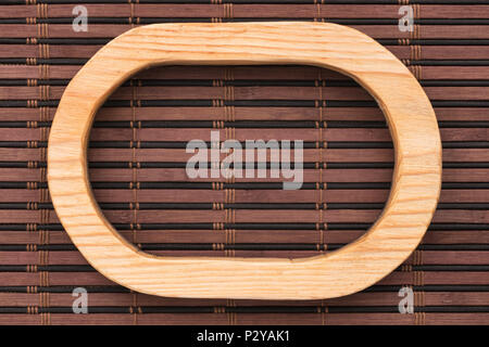 Beautiful wooden frame cut from a solid board, lies on a dark bamboo mat. View from above Stock Photo